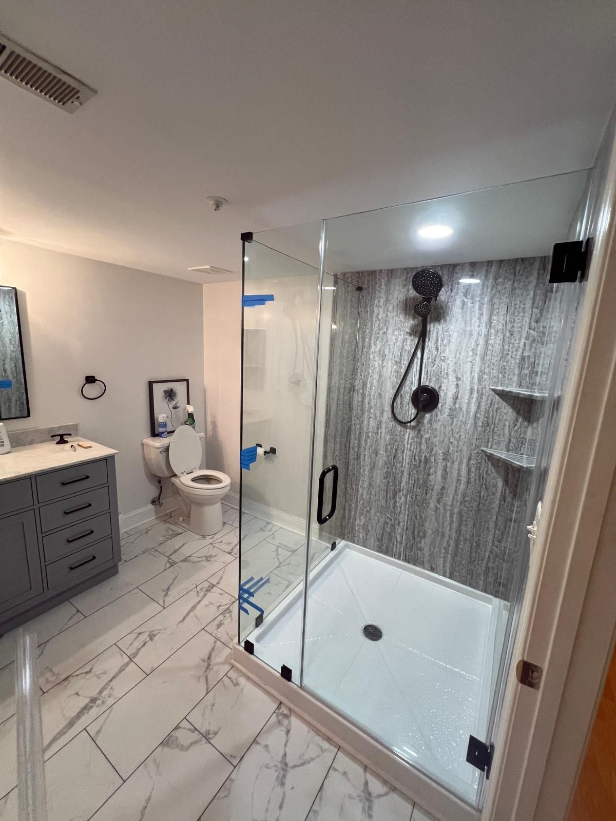 Modern bathroom with glass shower, gray walls, white floor, and vanity.