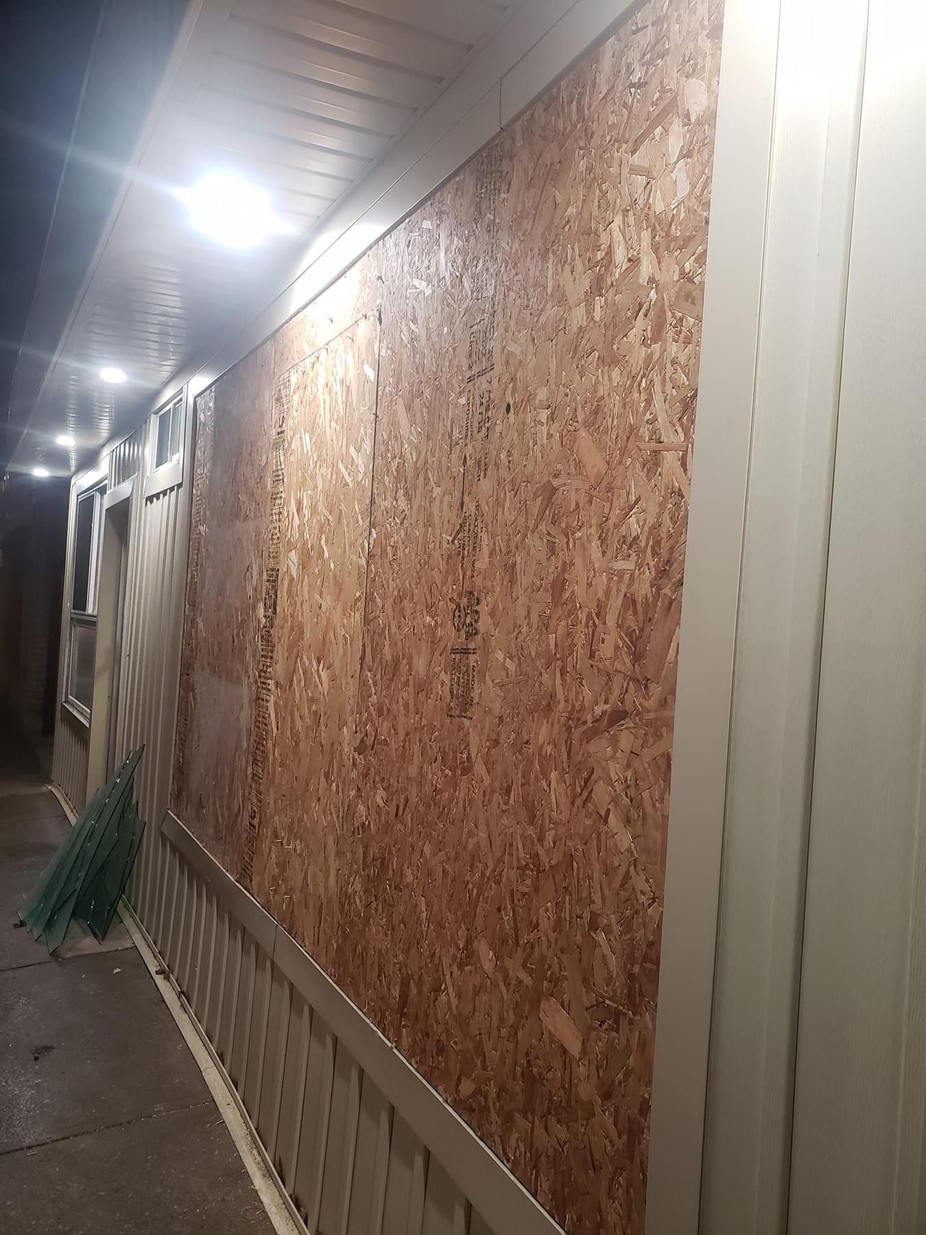 Exterior wall covered in brown wood panels. White trim, concrete walkway, and ceiling.
