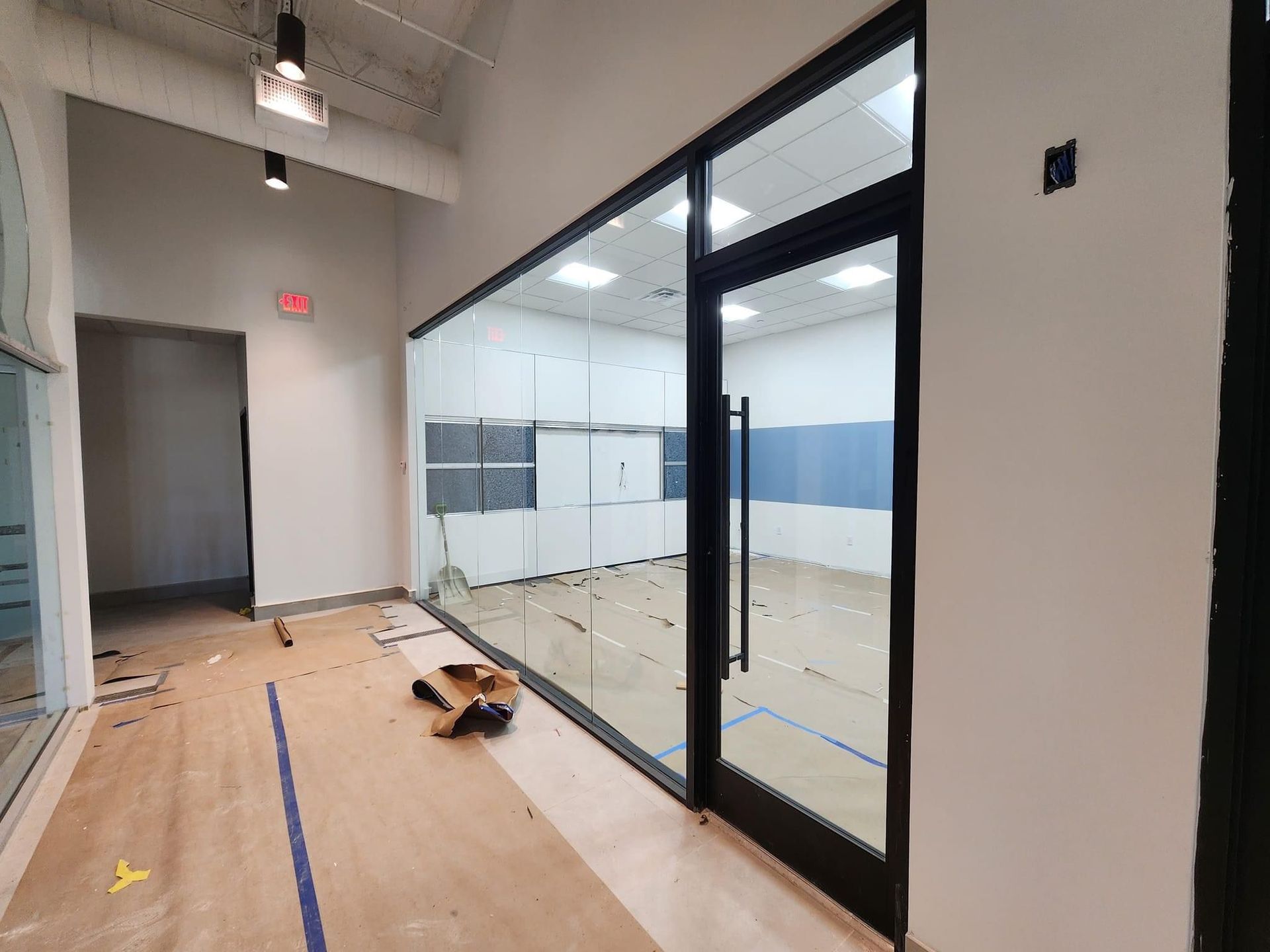 Interior view of a room with a glass-walled enclosure, wooden floors, and an open doorway.