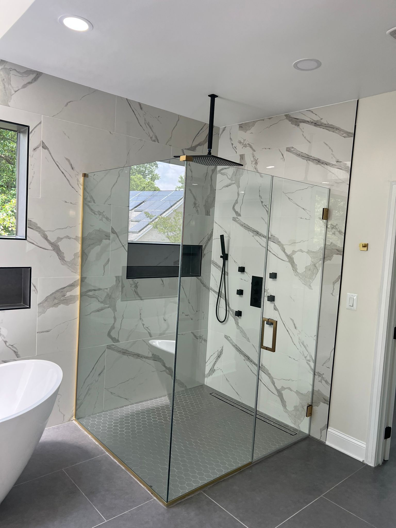 Modern bathroom with marble walls and a glass shower enclosure.