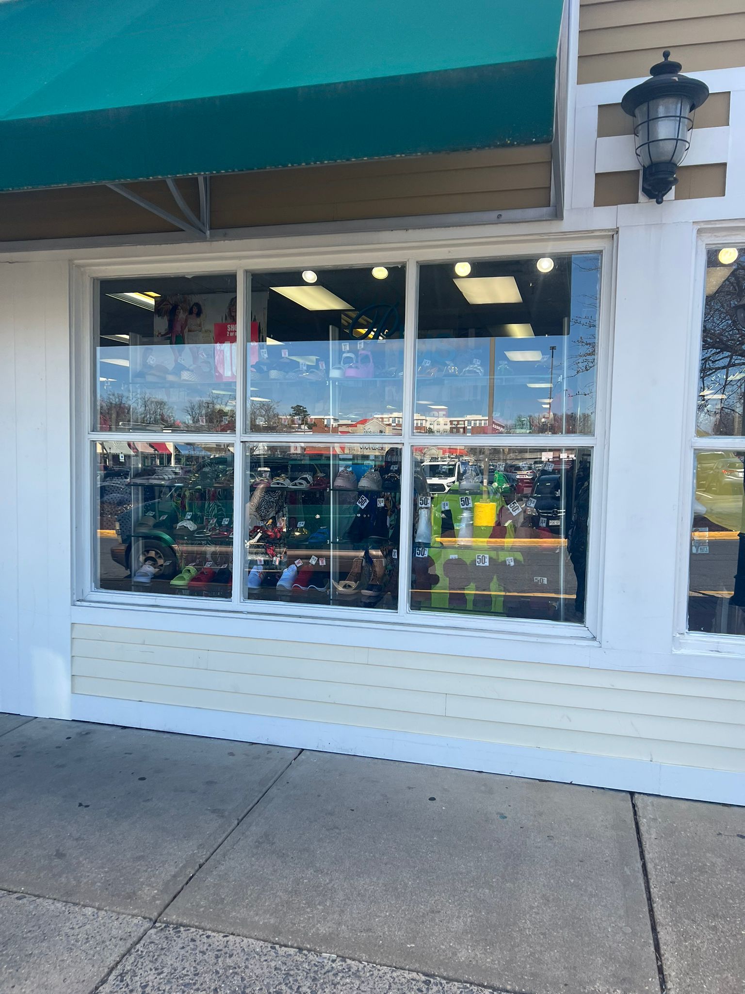 Shopfront with large window, green awning, and sidewalk.