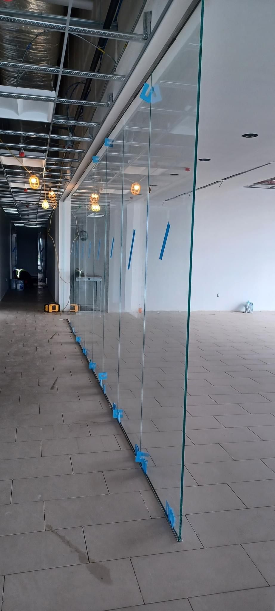Glass partition in a construction area, held in place with blue adhesive tabs.