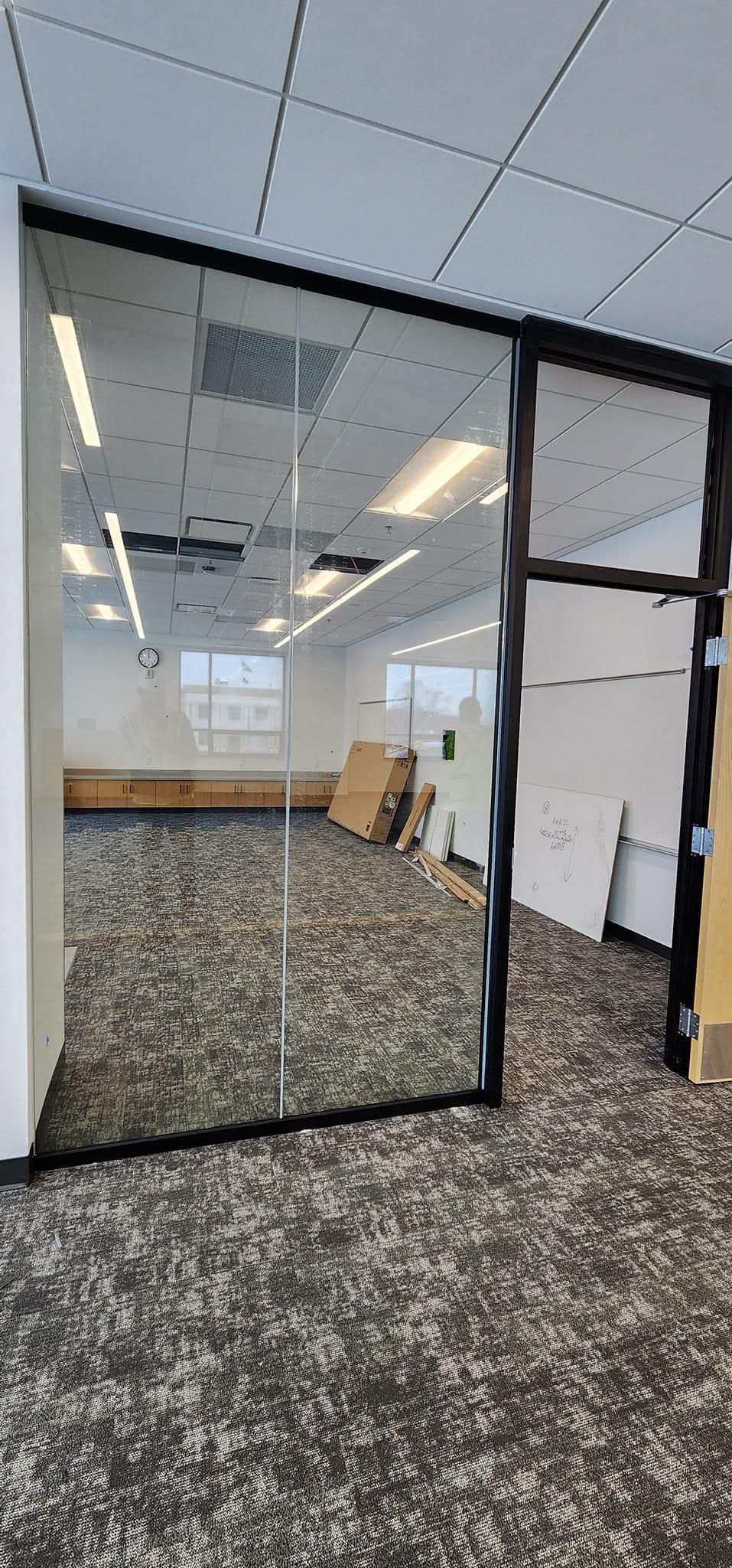 Interior office space with a glass wall and carpet flooring.