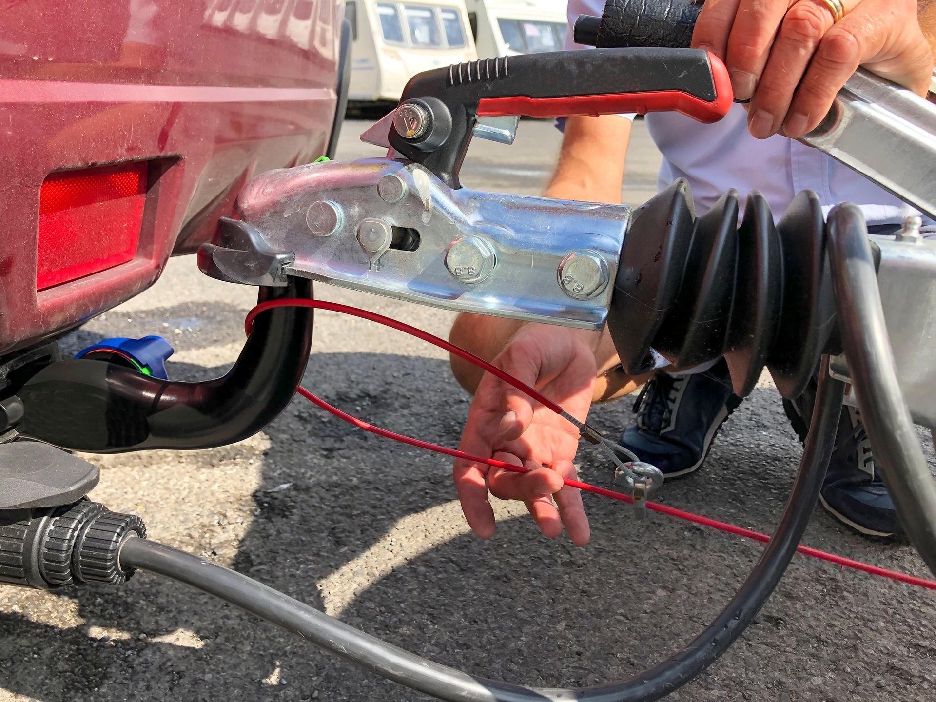 Installing towing brake controllers and safety red cable on a trailer hitch.