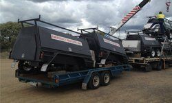 A black and white trailer is parked next to a truck.