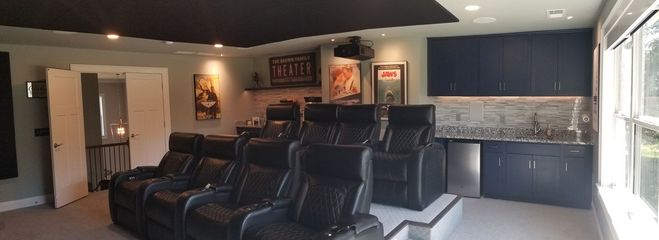 A home theater with black leather seats and a projector.