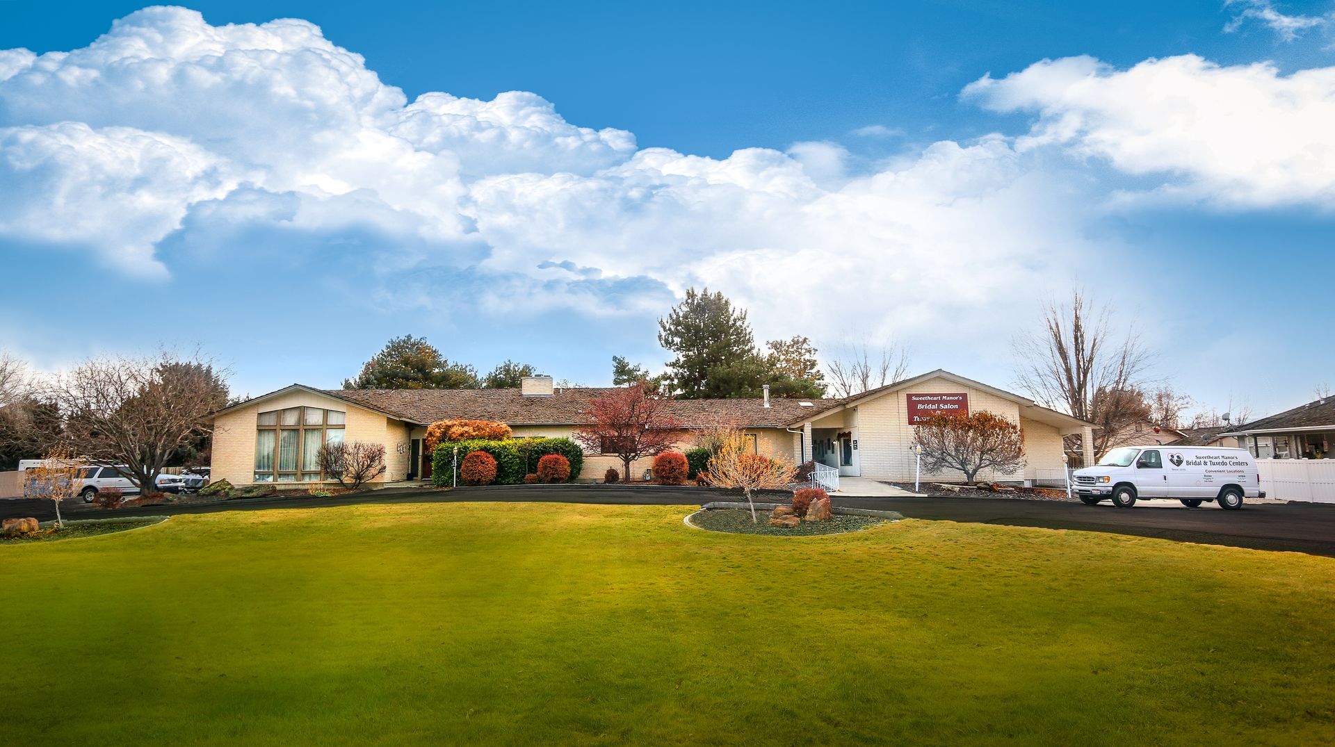 A white van is parked in front of a house with a large lawn.
