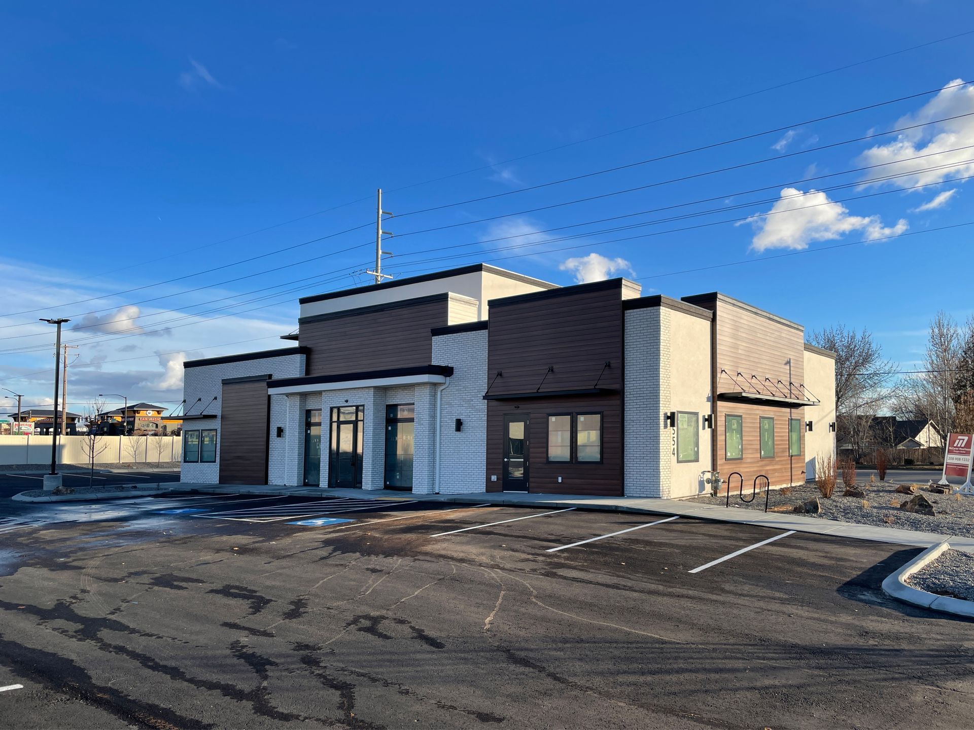 A large building with a lot of windows is sitting in a parking lot.