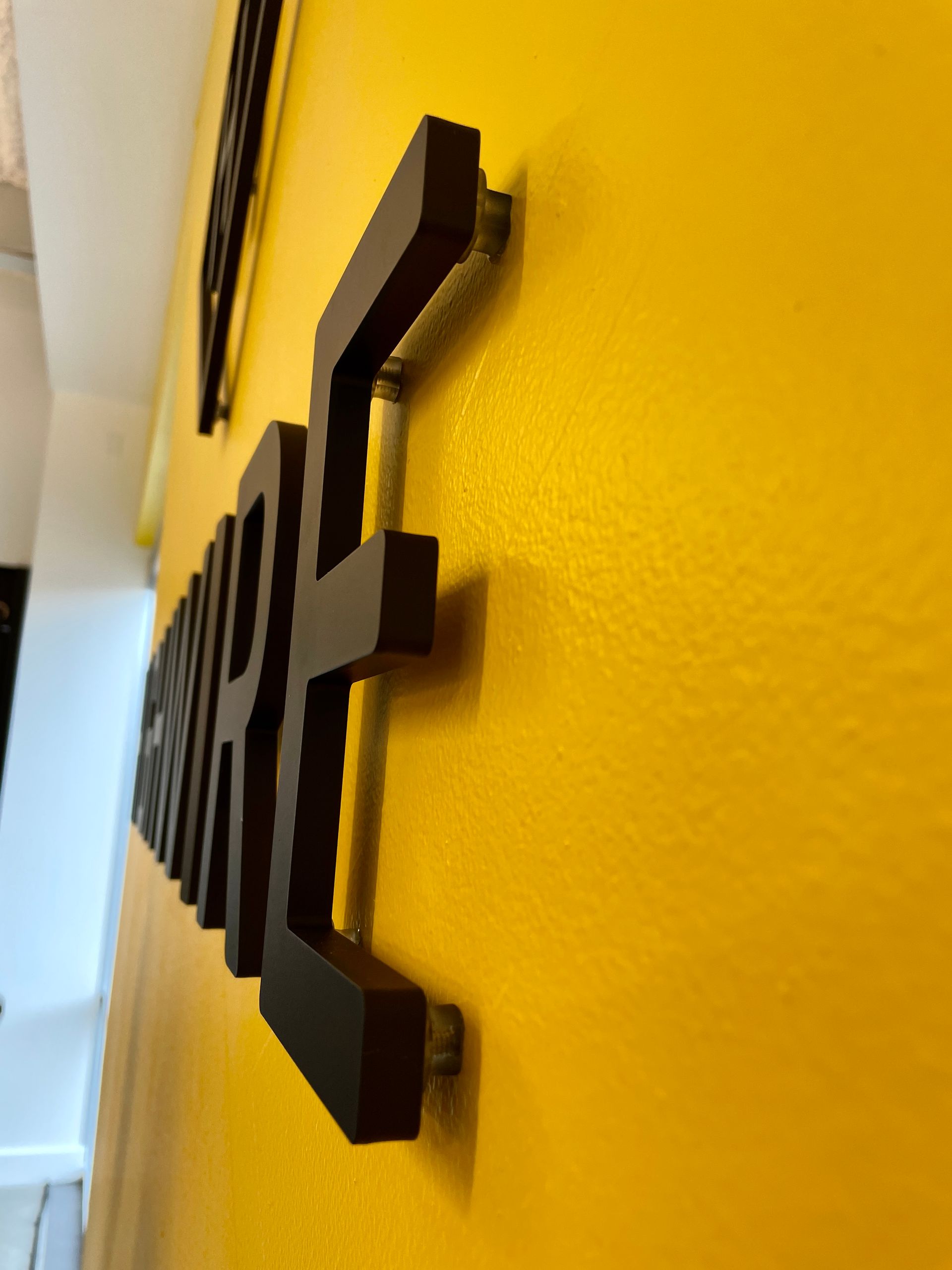 A yellow wall with a black sign on it