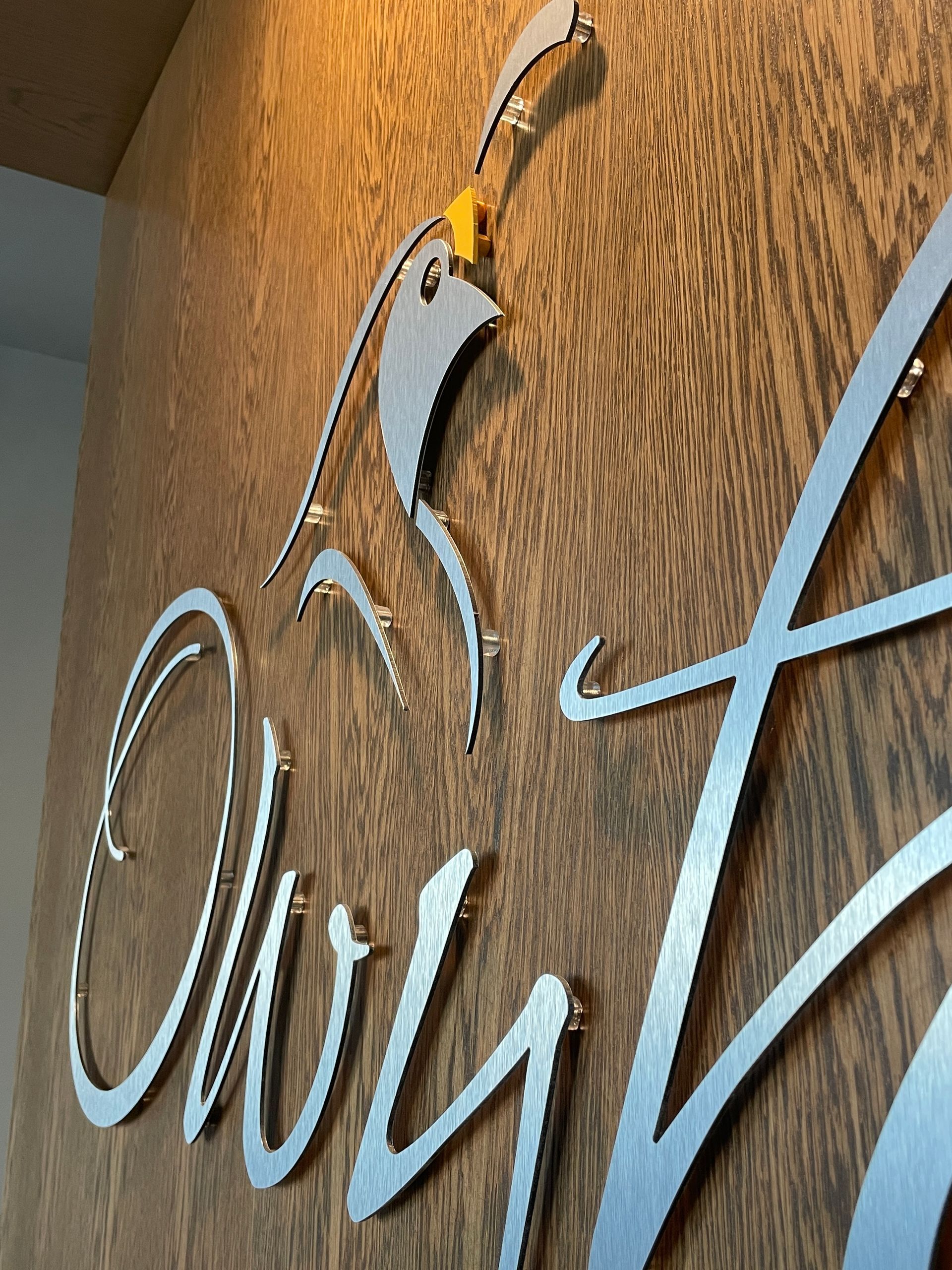 A close up of a sign on a wooden wall with a bird on it.