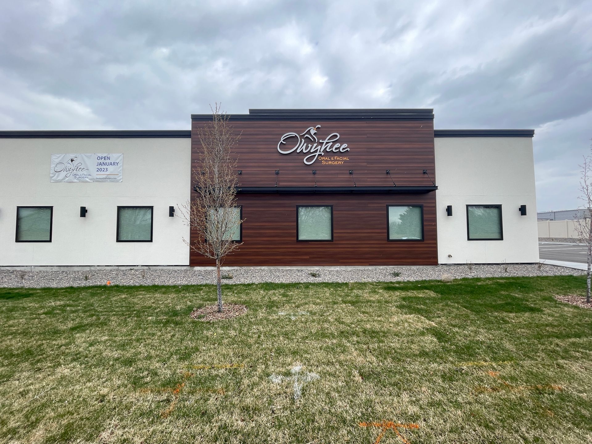 A white building with a wooden facade and a tree in front of it.