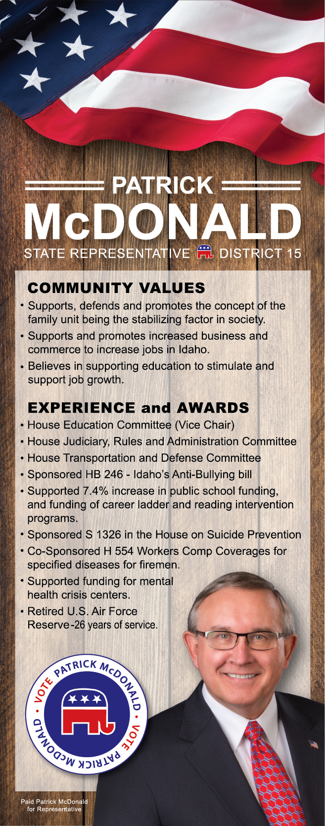 A man in a suit and tie is standing in front of an american flag.