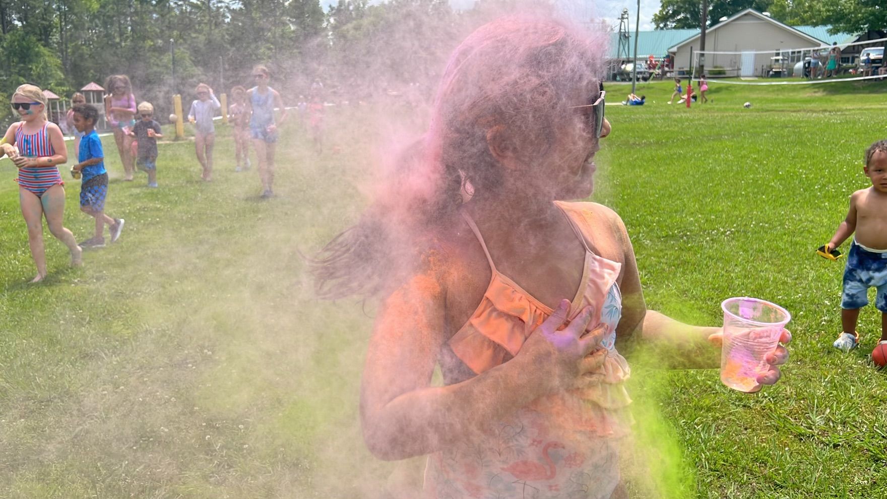 A group of children are playing in a park with colored powder.