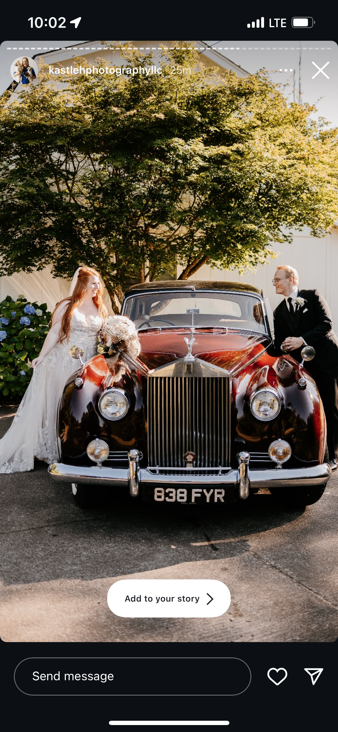 Bride in a white dress with a veil, seated in a classic black car, holding dark purple calla lilies.