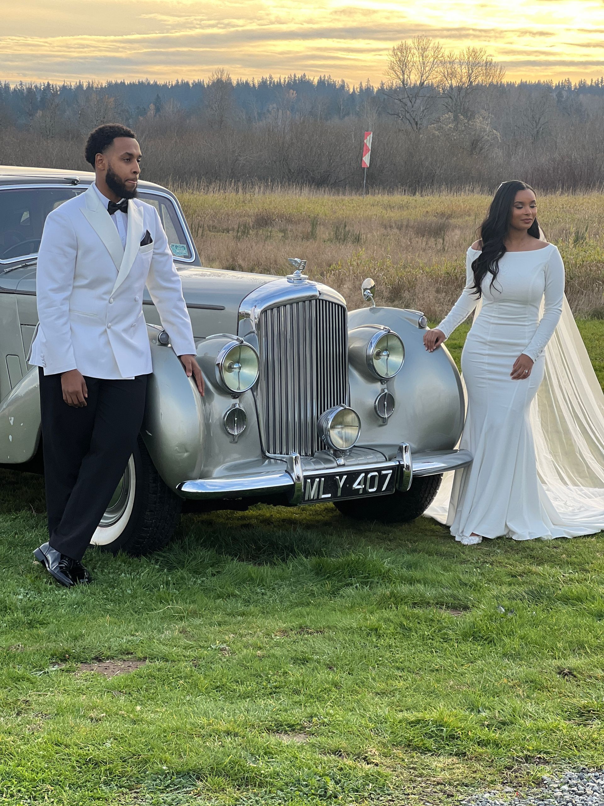 White classic Jaguar convertible in front, other vintage cars blurred in the background.