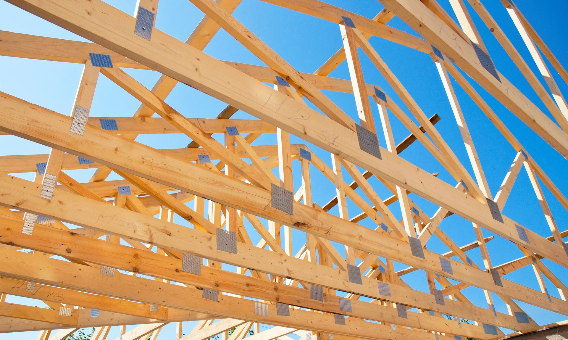 View of timber roof trusses looked from below against blue sky. View of timber roof trusses looked from below against blue sky.