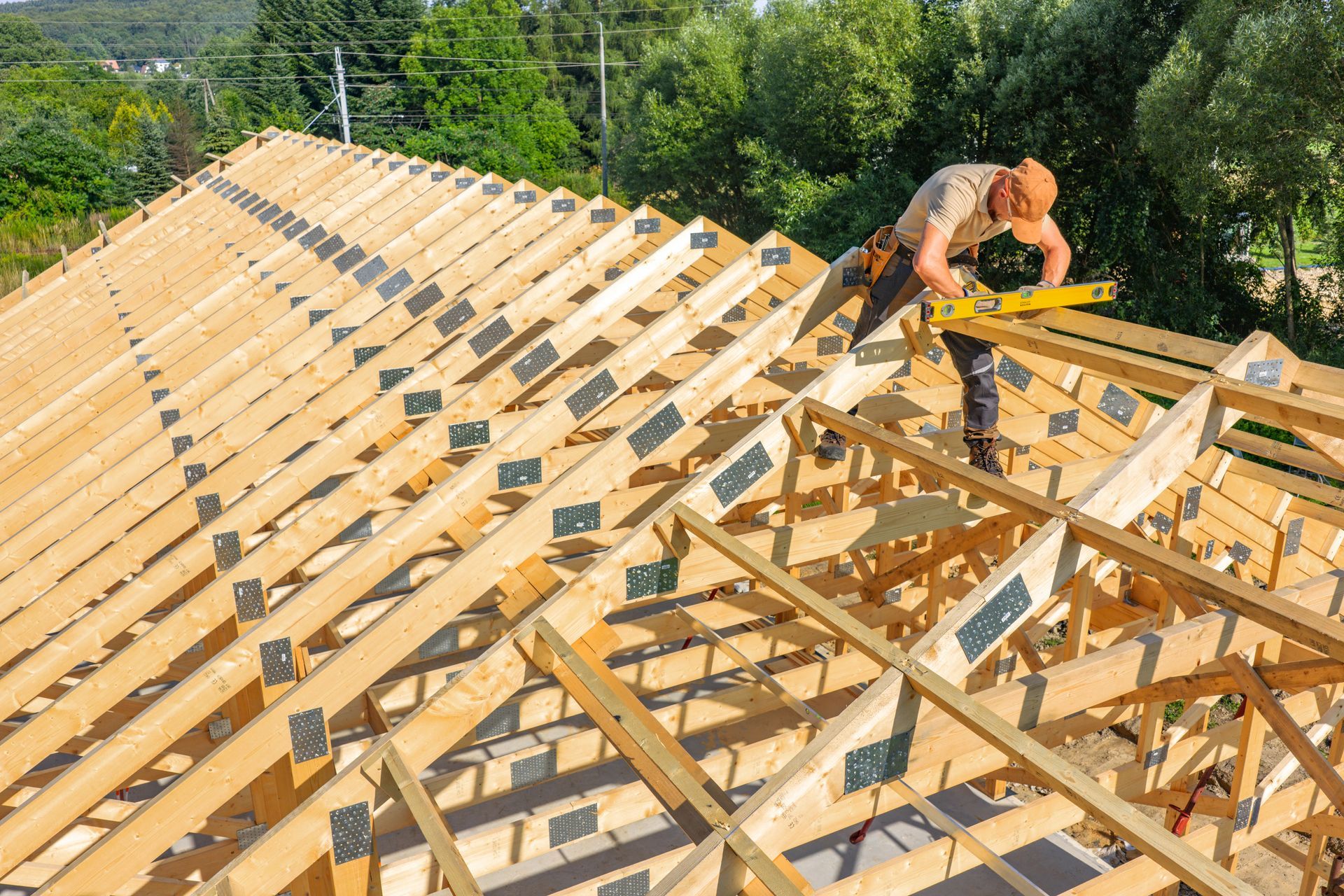 A construction worker carpenter measuring roof trusses on a sunny day outdoors. A construction worker carpenter measuring roof trusses on a sunny day outdoors.