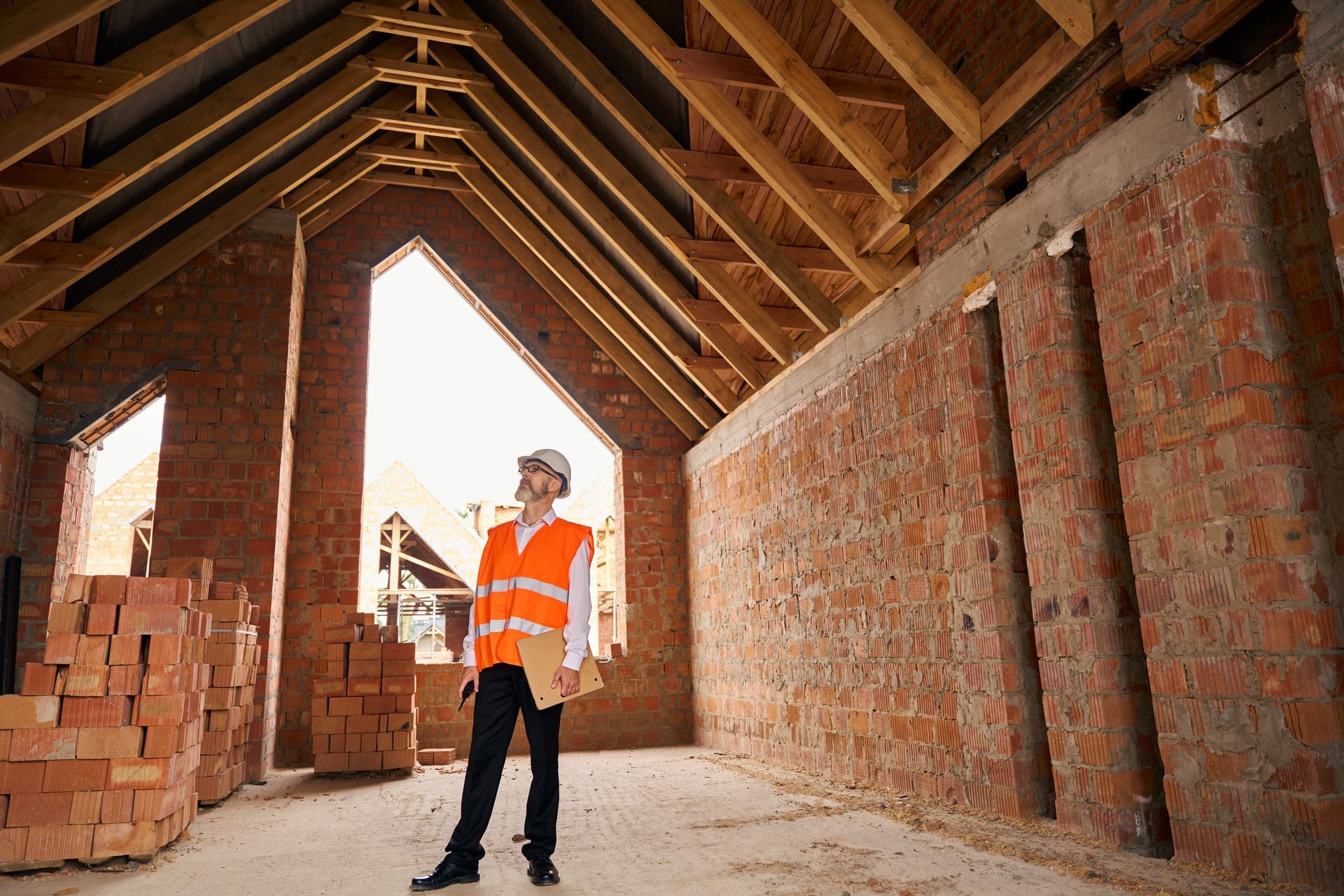 Construction superintendent inspecting timber roof trusses from inside the building. Construction superintendent inspecting timber roof trusses from inside the building.