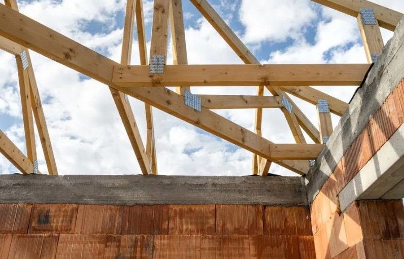 Exterior view of a building with straw bale walls, two windows with metal frames, and weathered appearance.