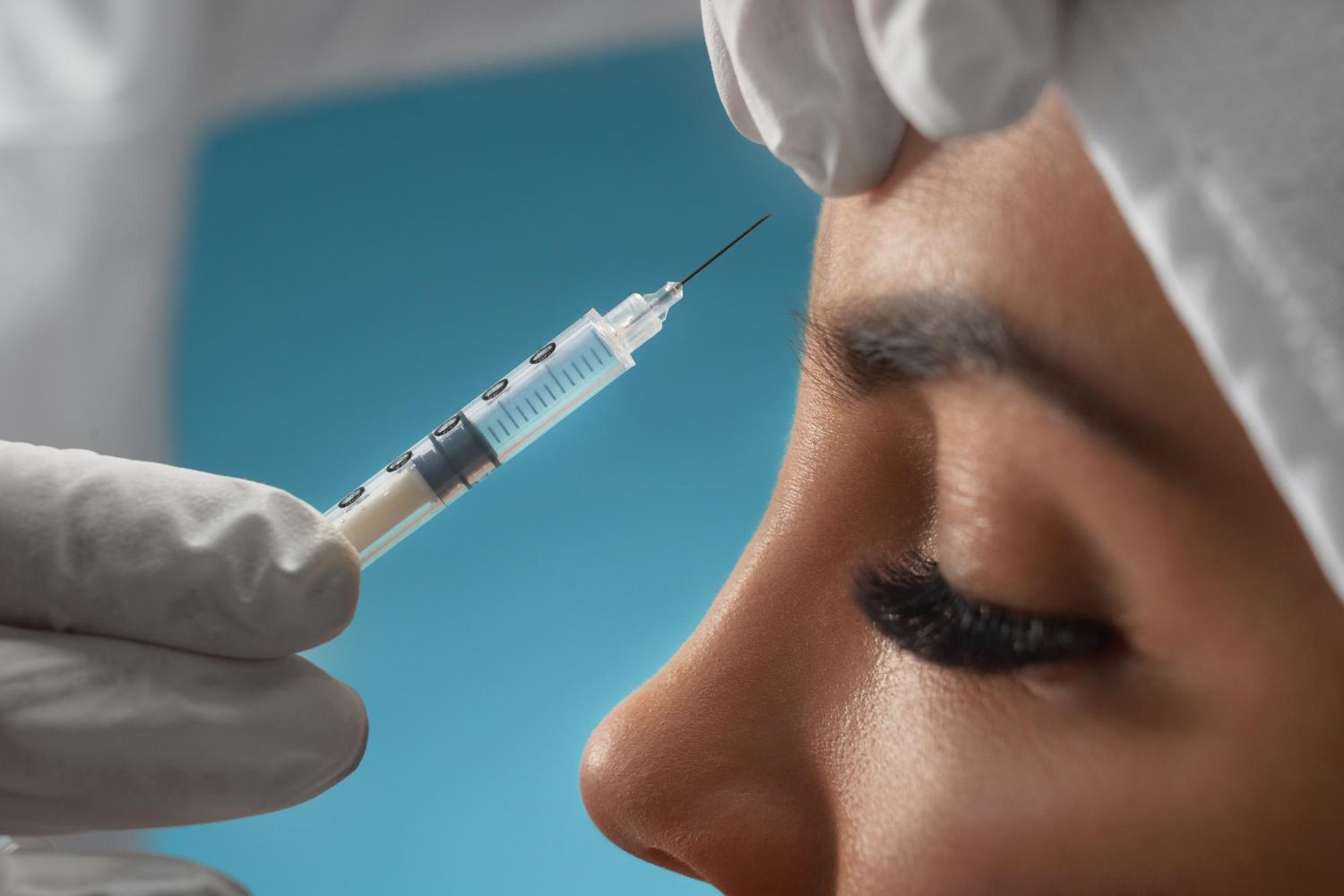A woman is getting a botox injection in her forehead.
