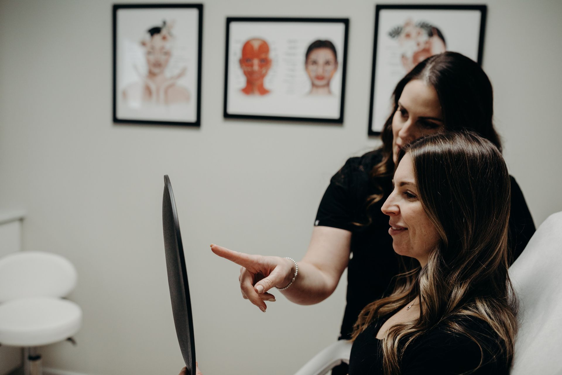 Two women are looking at an x-ray of a woman 's face.