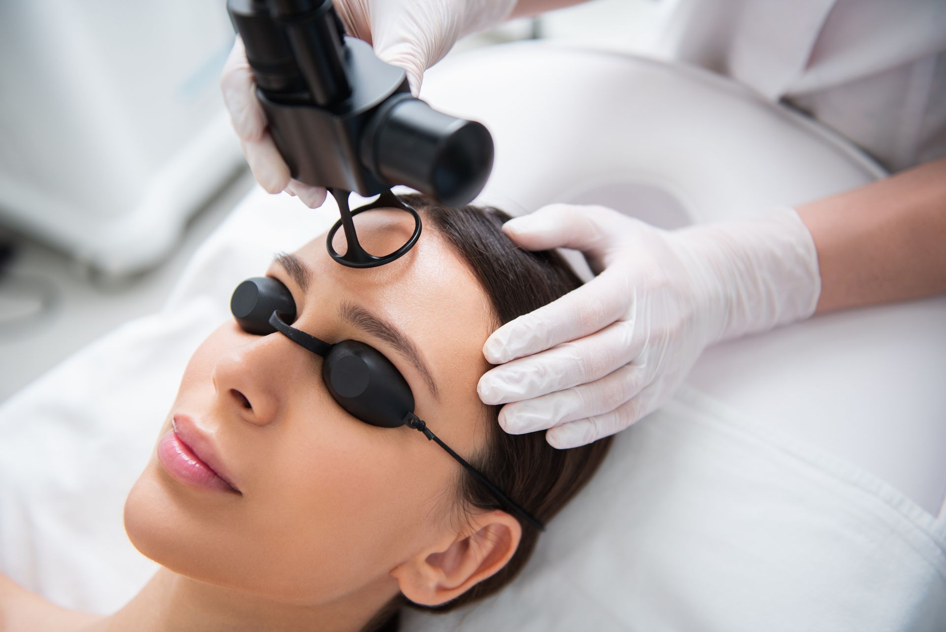 A woman is getting a laser treatment on her face.