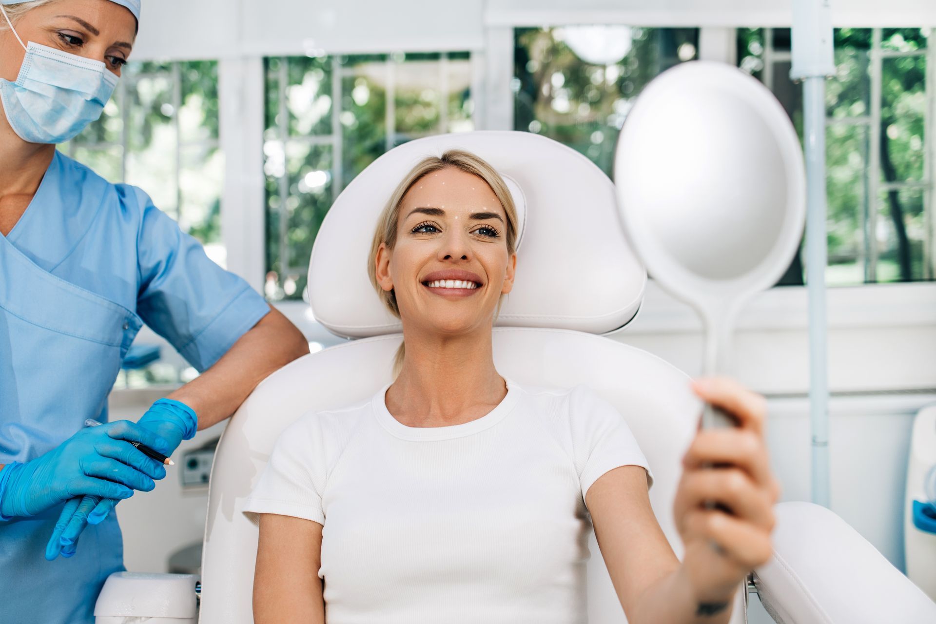 A woman is smiling while sitting in a dental chair.