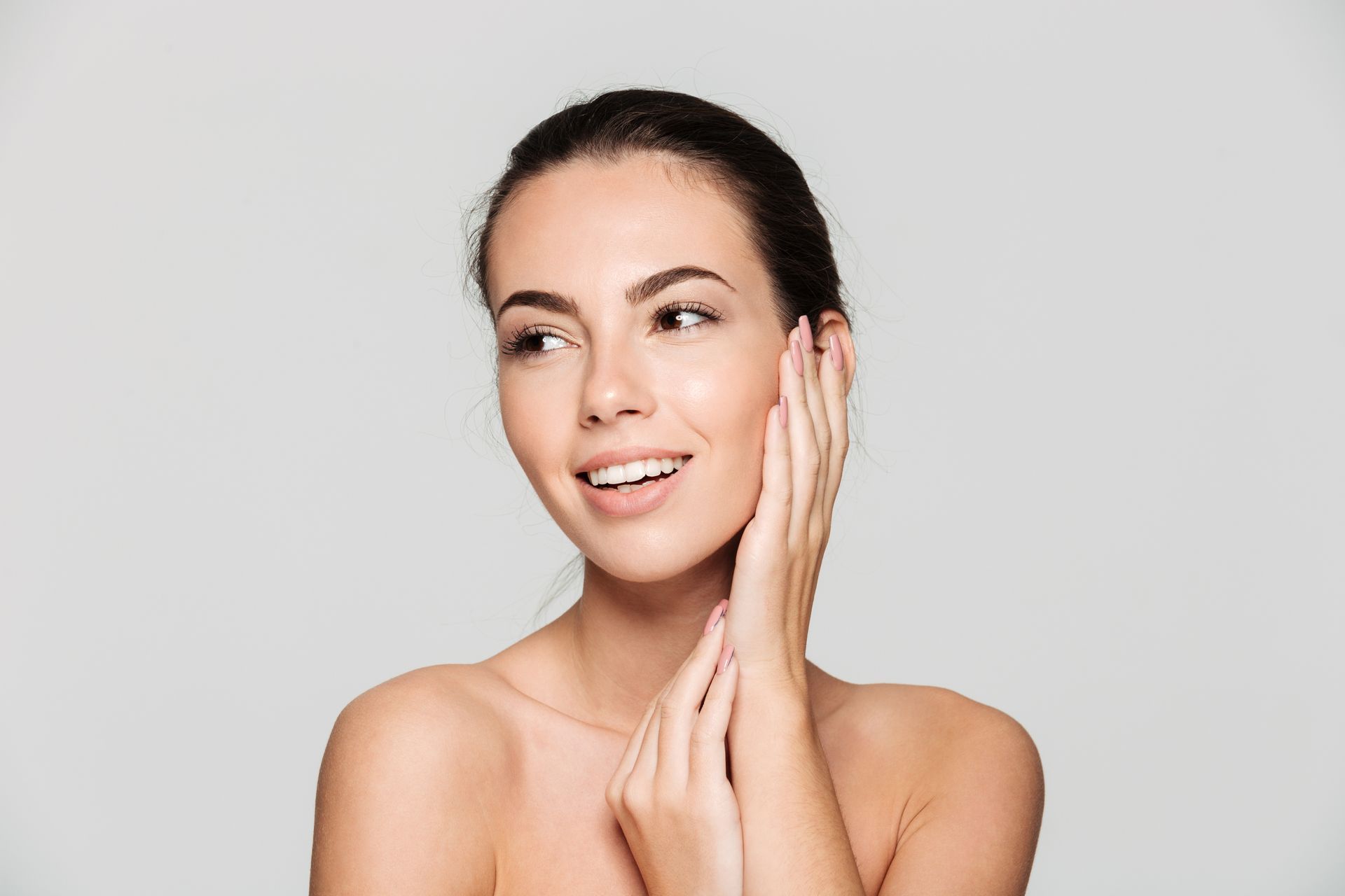 Portrait of a smiling woman touching her face over gray background