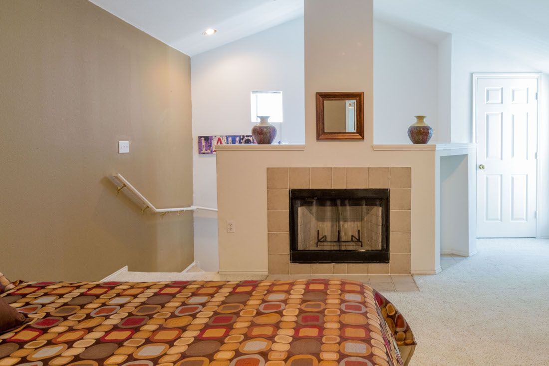 Cozy bedroom featuring a fireplace and staircase