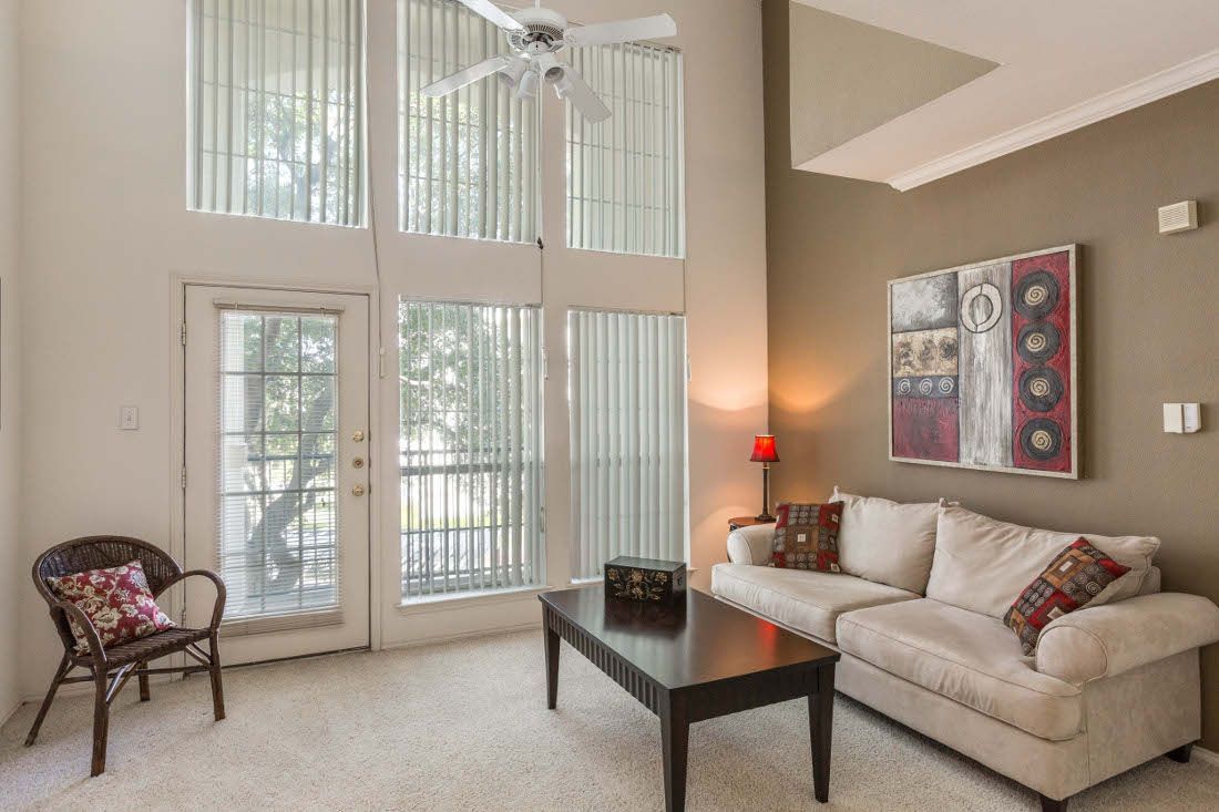 Living room with large windows, beige sofa, and decorative table.