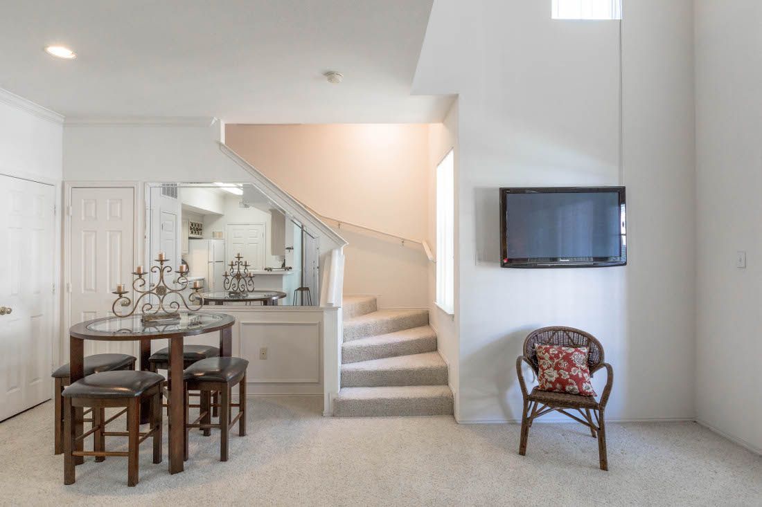 Interior view of an apartment living area with a dining table and staircase.