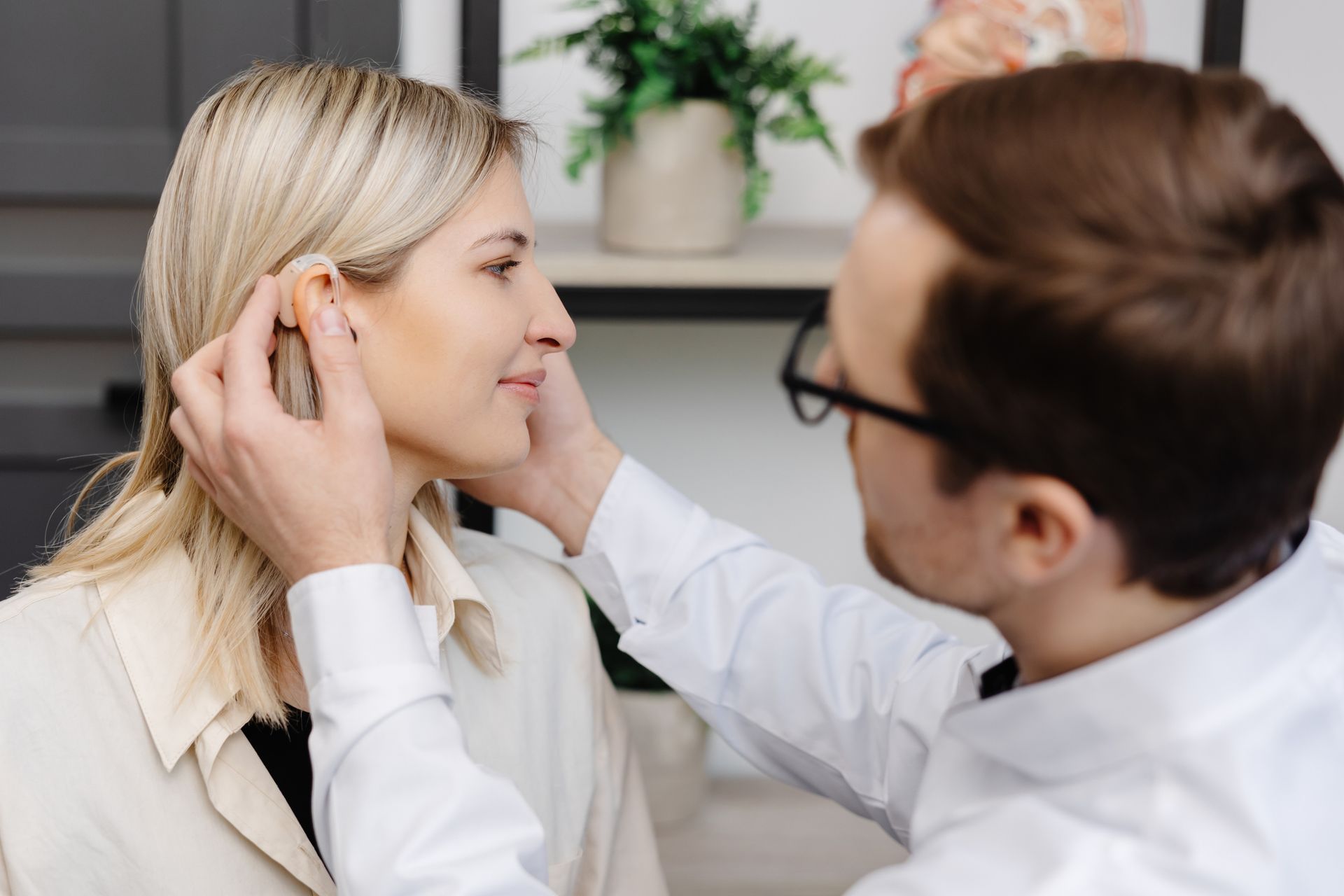A doctor is putting a hearing aid in a patient. A doctor is putting a hearing aid in a patient.