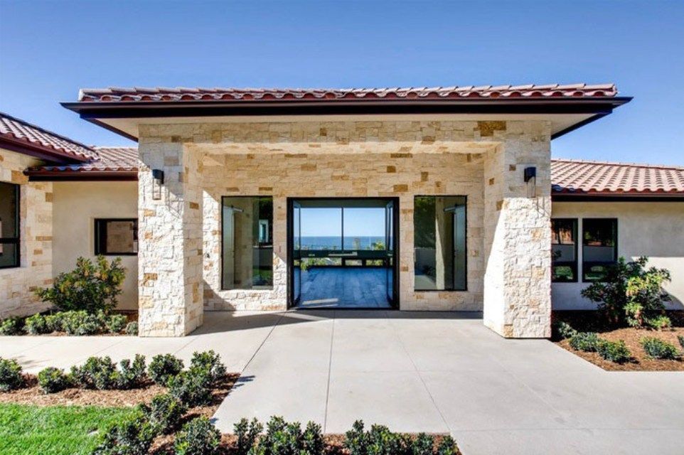 Front entrance of luxury house with wooden door and stone facade.