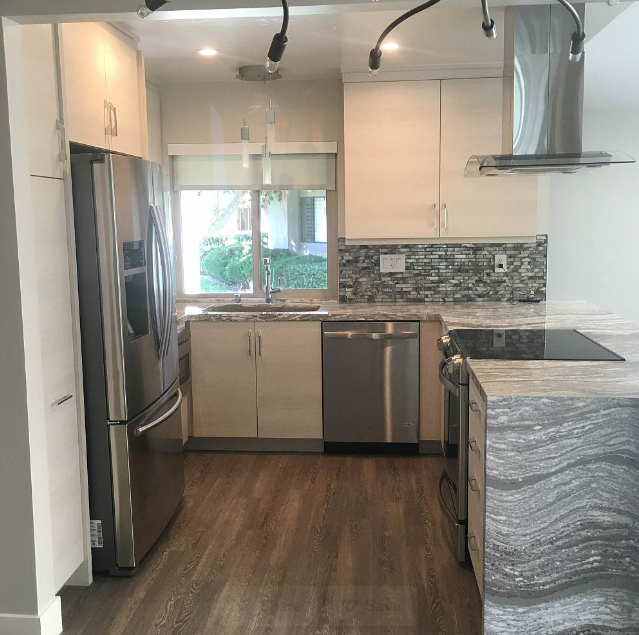 Contemporary kitchen with stainless steel appliances and glass cabinets.