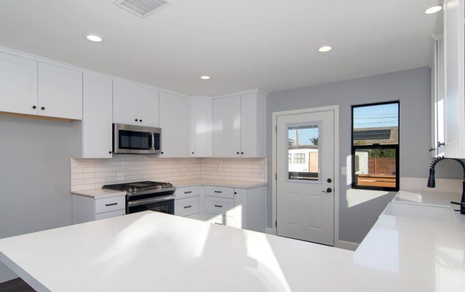 Minimalist white kitchen with island and modern lighting.