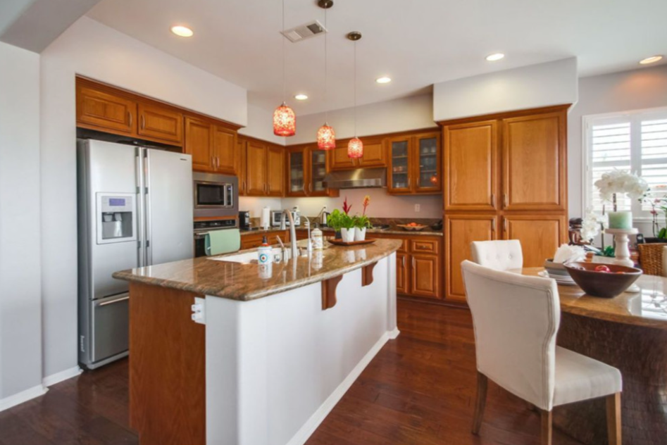 A teal metal fence with a gate encloses a garden on a sunny day. 