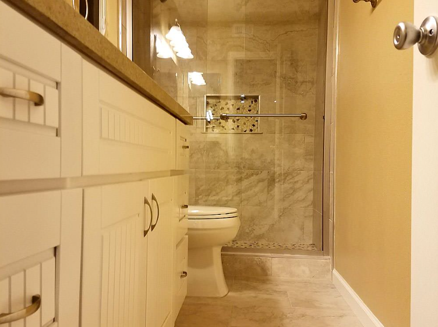 Beige bathroom interior with vanity cabinet and wall lighting.