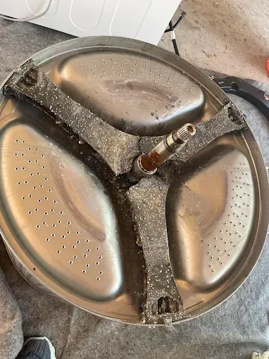 Washing machine drum with damaged agitator and worn rubber pieces.