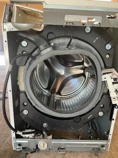 Washing machine's interior with drum, rubber seal, and various components visible.
