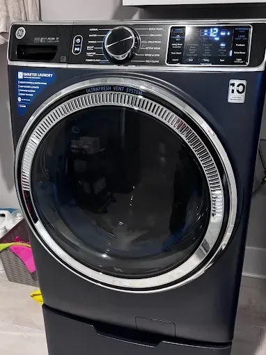Dark blue GE front-load washing machine with chrome accents, buttons, and control panel.