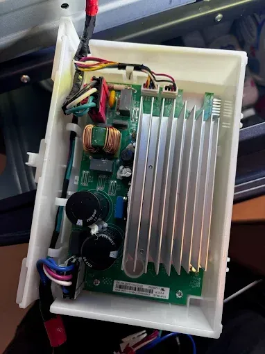 Printed circuit board with heat sink inside a white plastic enclosure. Wires and components visible.