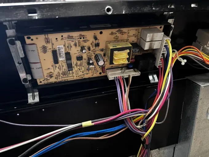 Circuit board with multicolored wires inside an appliance.