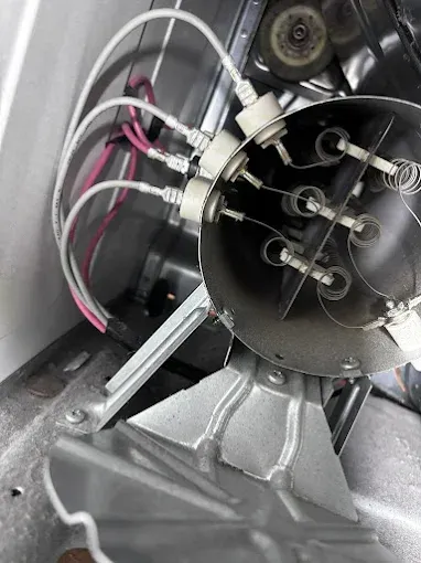 Close-up of a dryer's heating element, with wires attached to cylindrical components.