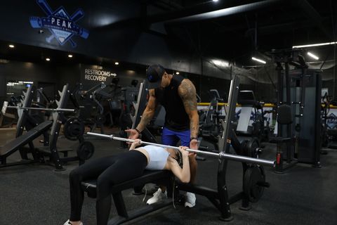 A shirtless man is lifting a barbell in a garage.