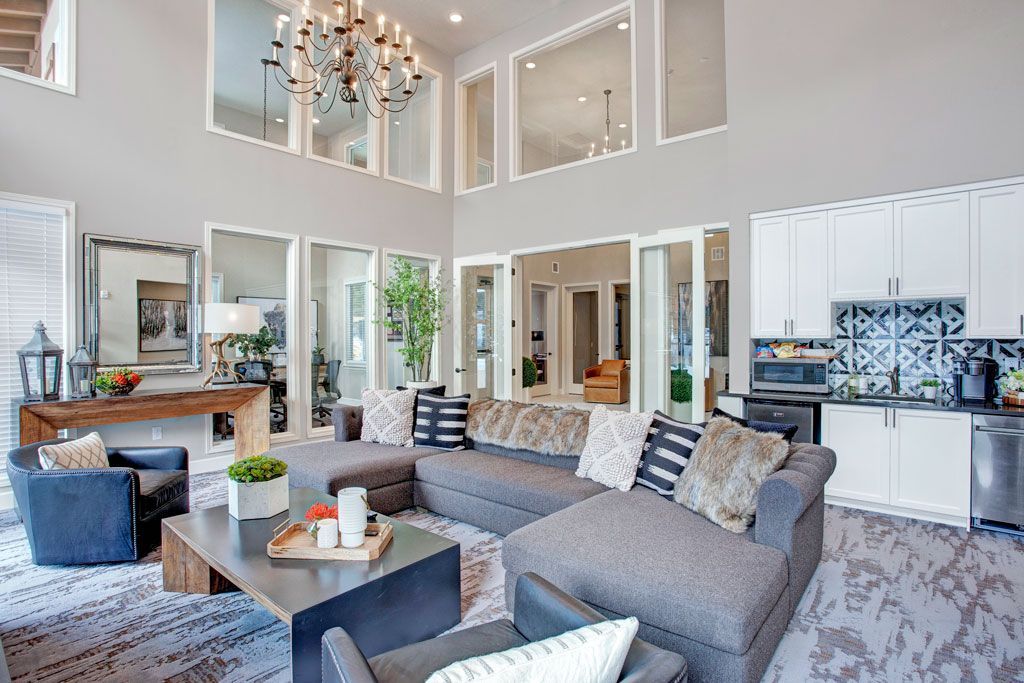 A living room with a large sectional couch , chairs , a coffee table and a chandelier.