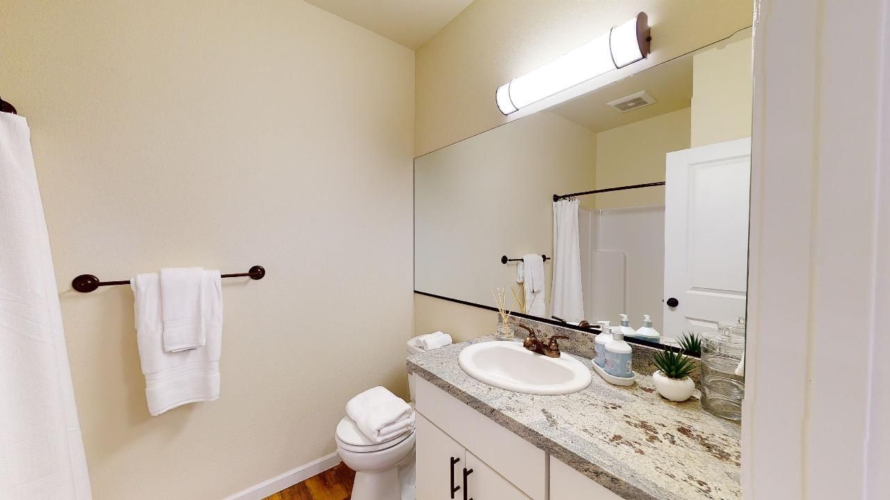 A bathroom with a toilet , sink , and mirror.