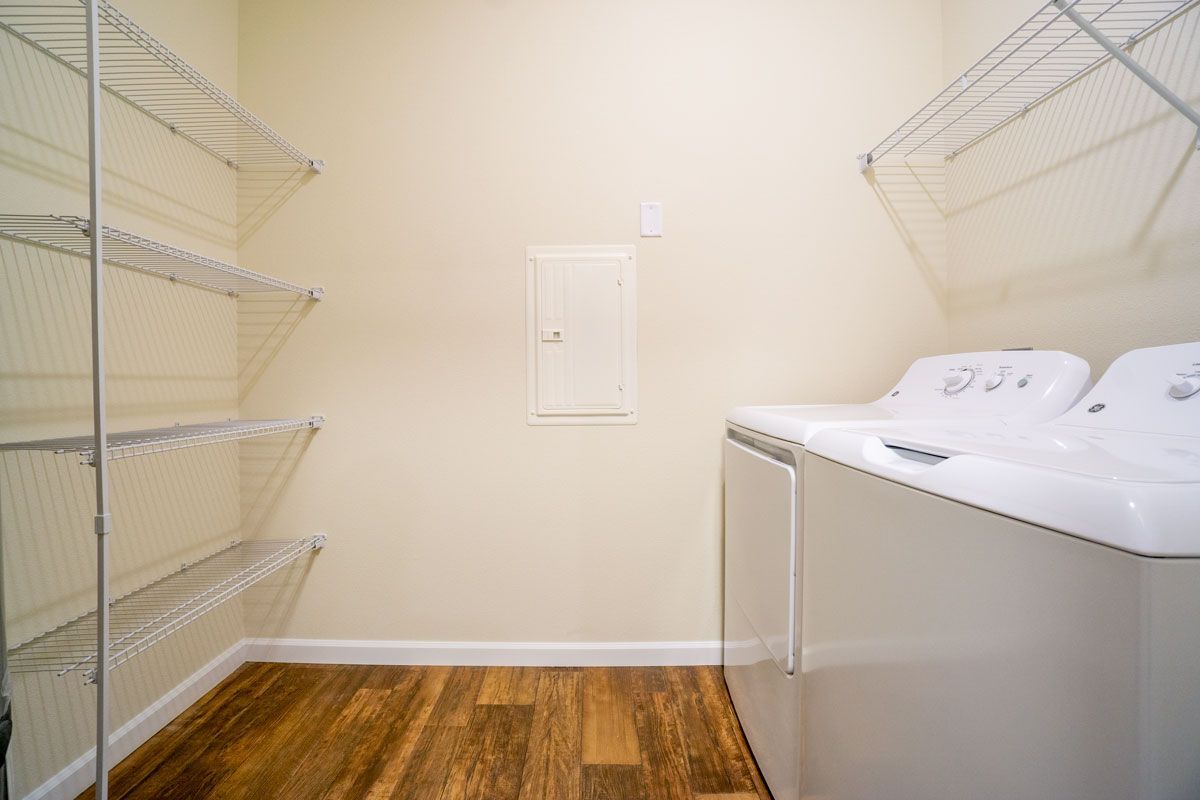 A laundry room with a washer and dryer and shelves.