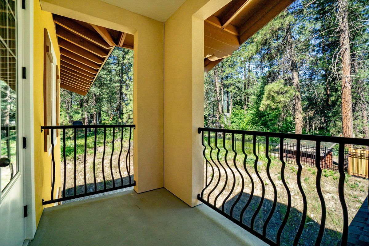 A balcony with a wrought iron railing overlooking a forest.