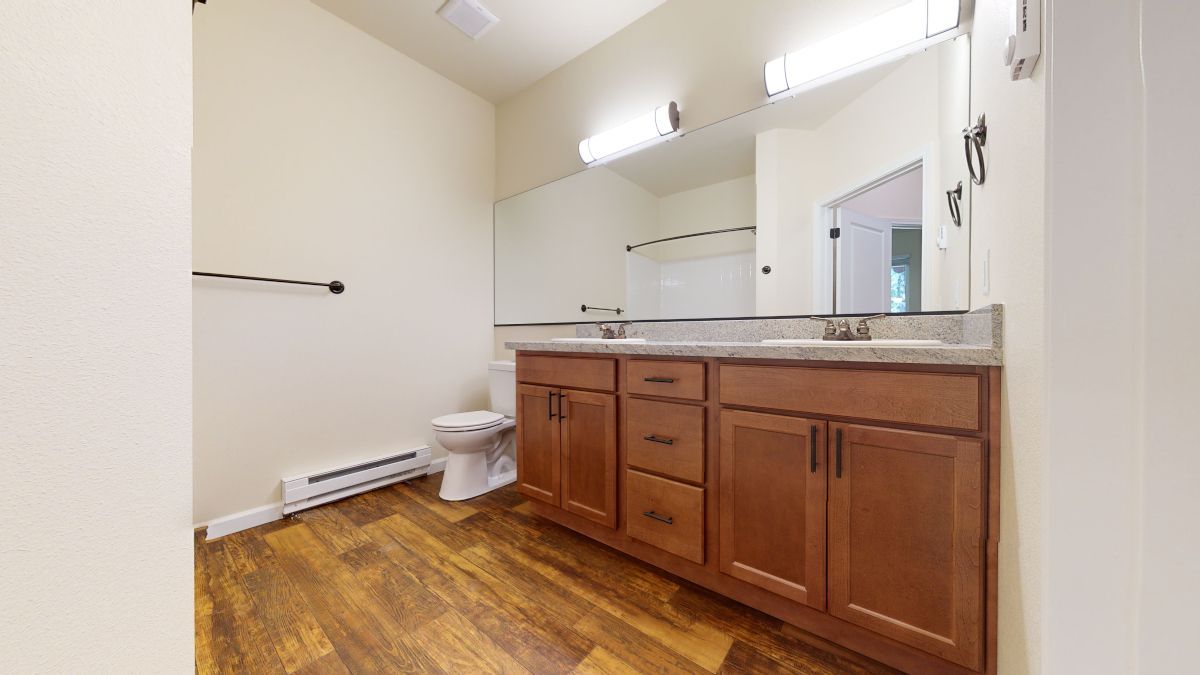A bathroom with two sinks , a toilet , and a mirror.