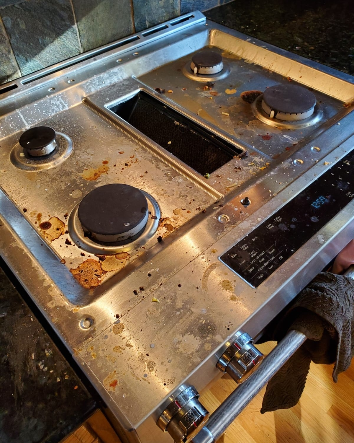 A dirty stove top oven is sitting on a counter in a kitchen.